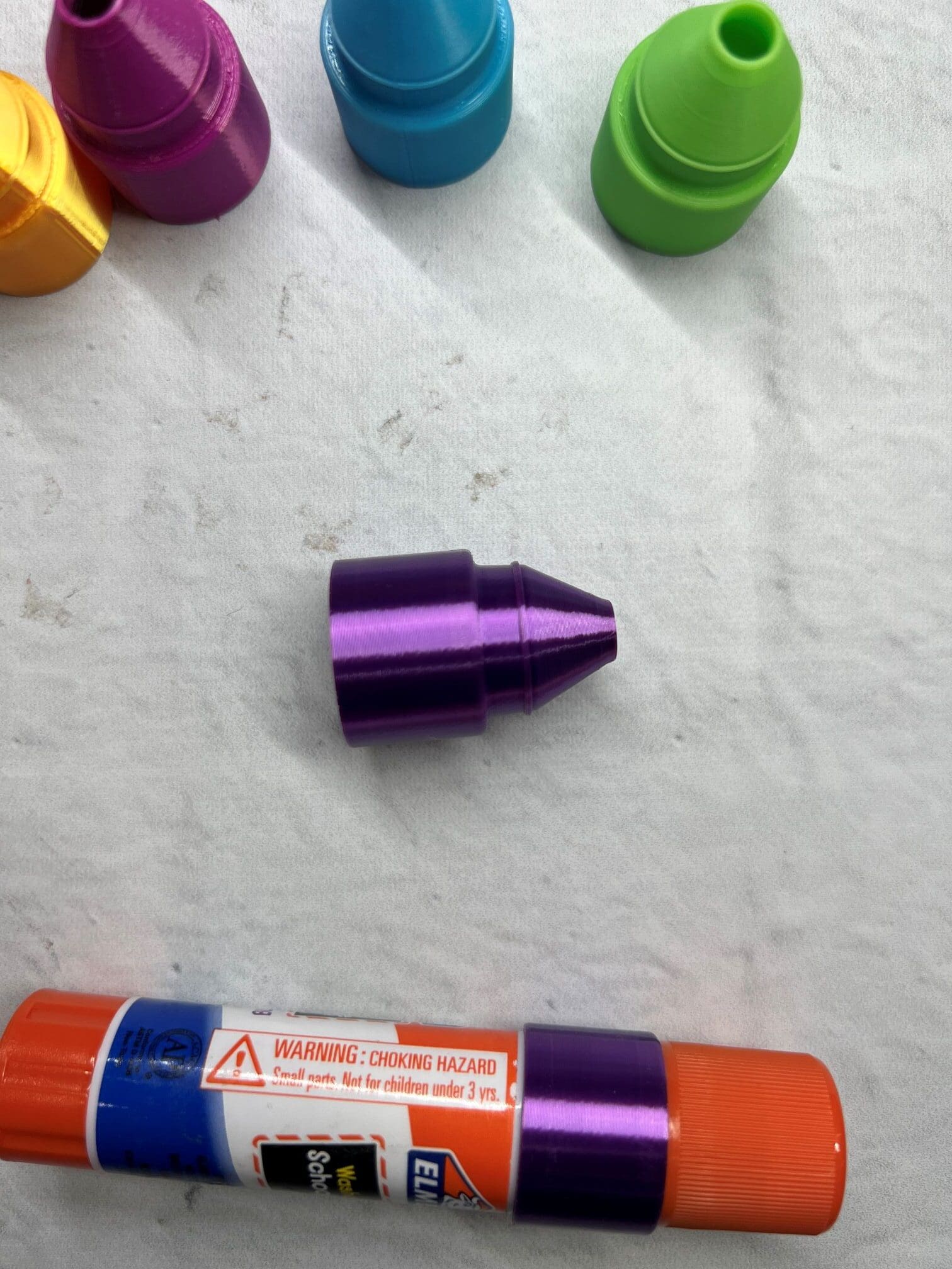 Purple metallic bullet-shaped object on a white surface.