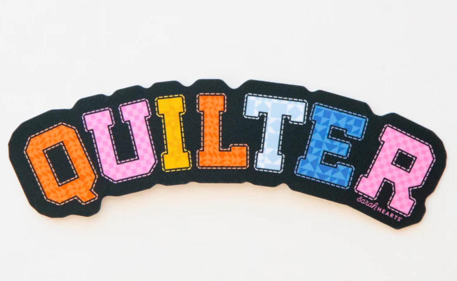 Colorful embroidered word 'QUILTER' on black fabric.