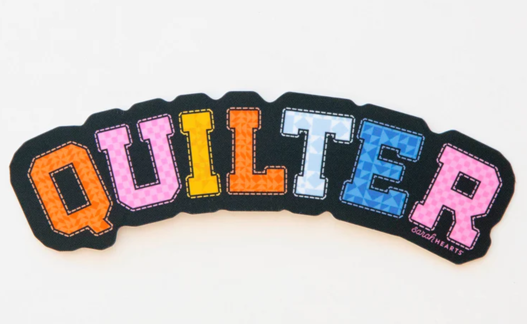 Colorful embroidered word 'QUILTER' on black fabric.