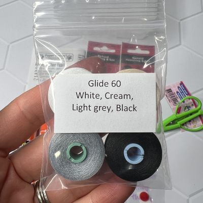 A hand holding a small plastic bag with four colored Glide 60 strings.