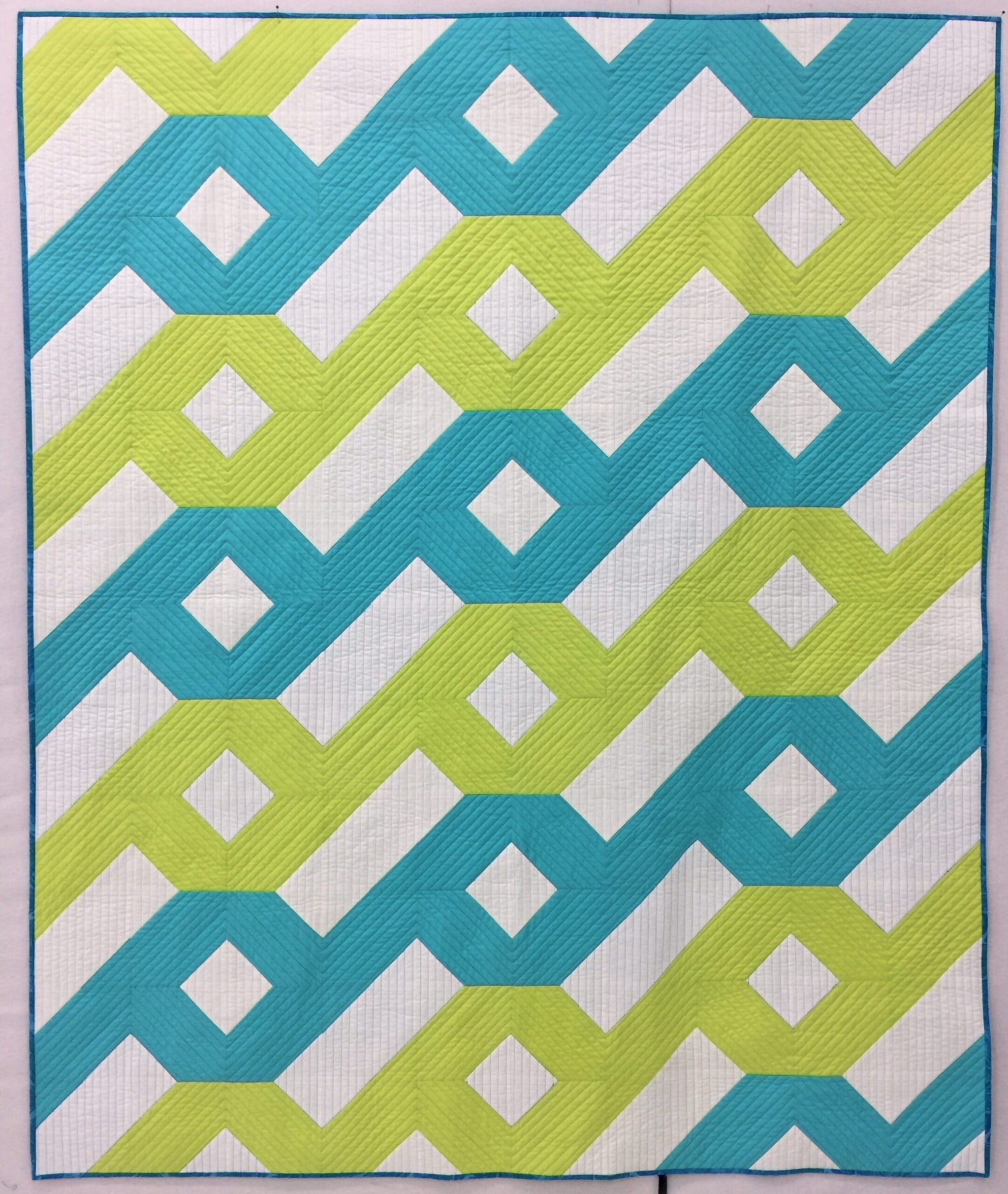 A blue and green quilt with an abstract design.