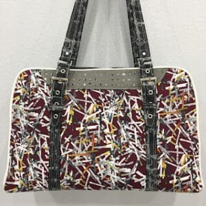Patterned handbag with black straps on wall.