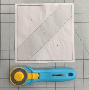 A blue rotary cutter next to a white paper.