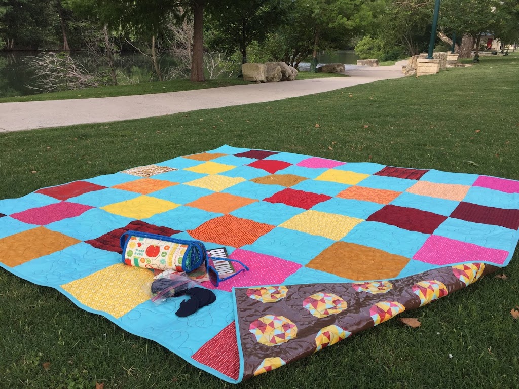 A blanket on the grass with clown faces and checkered pattern.