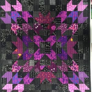 A quilt with purple and black designs on it.