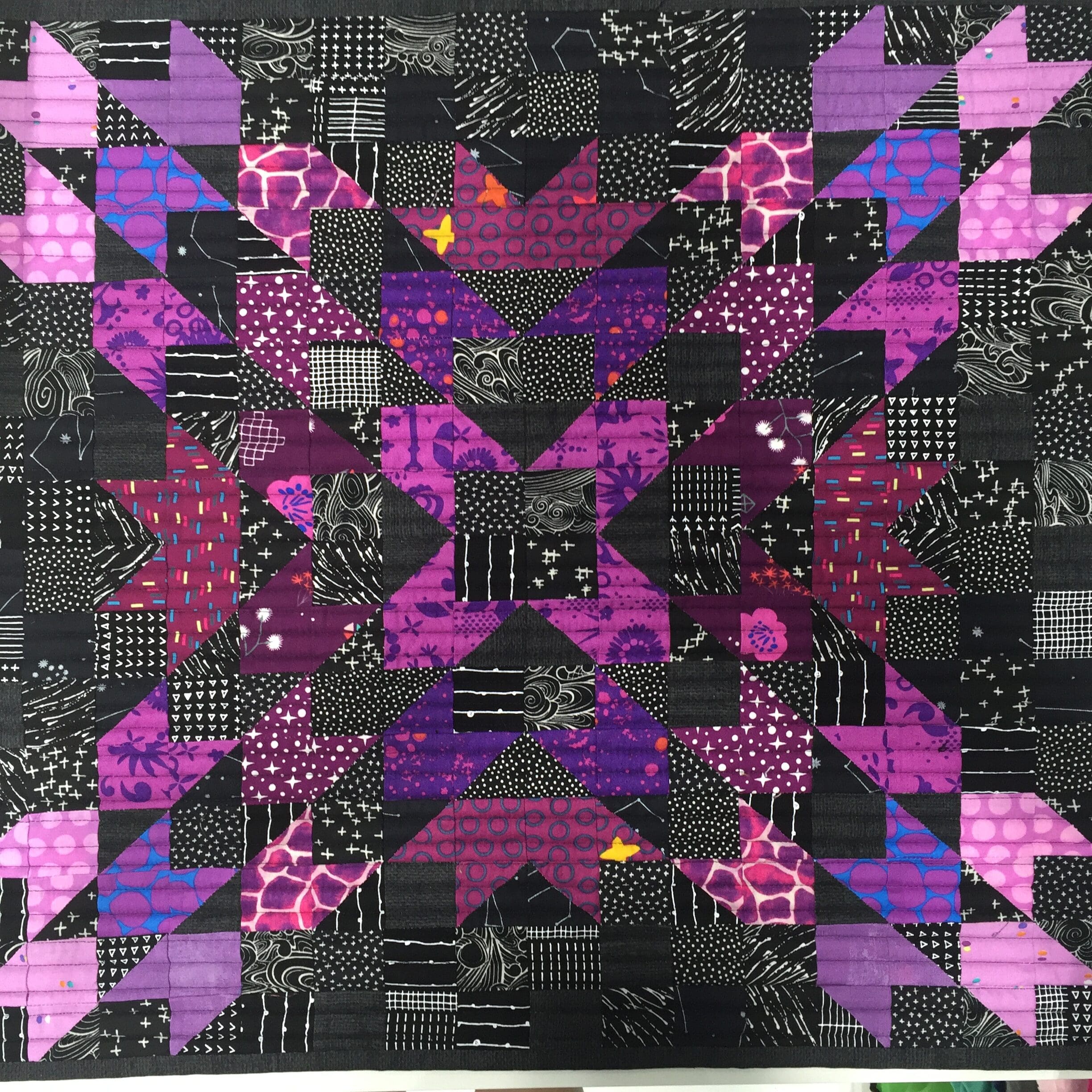 A quilt with purple and black designs on it.