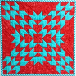 A red and blue quilt with a pattern of arrows.