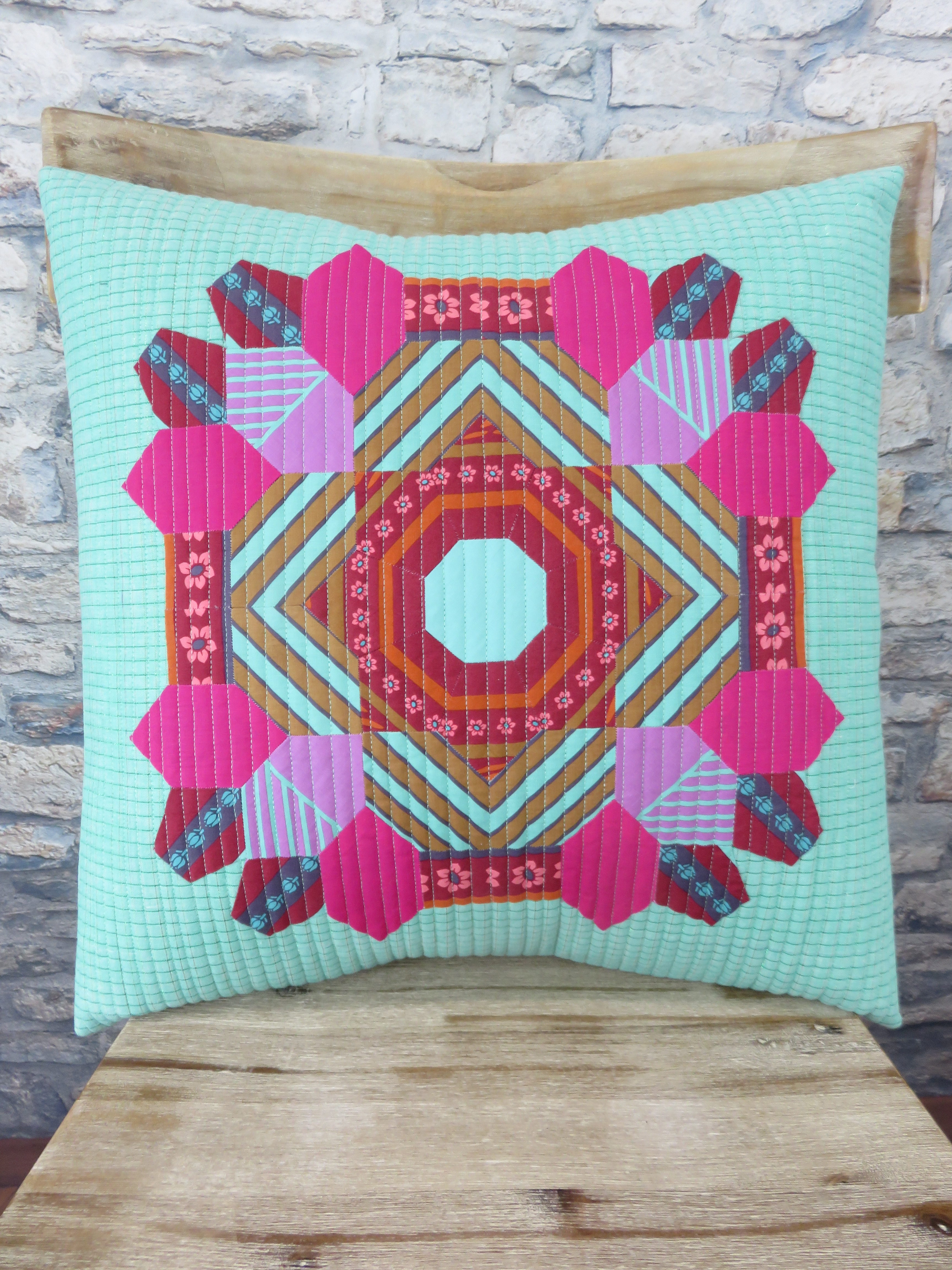 A colorful quilt is sitting on top of a wooden chair.