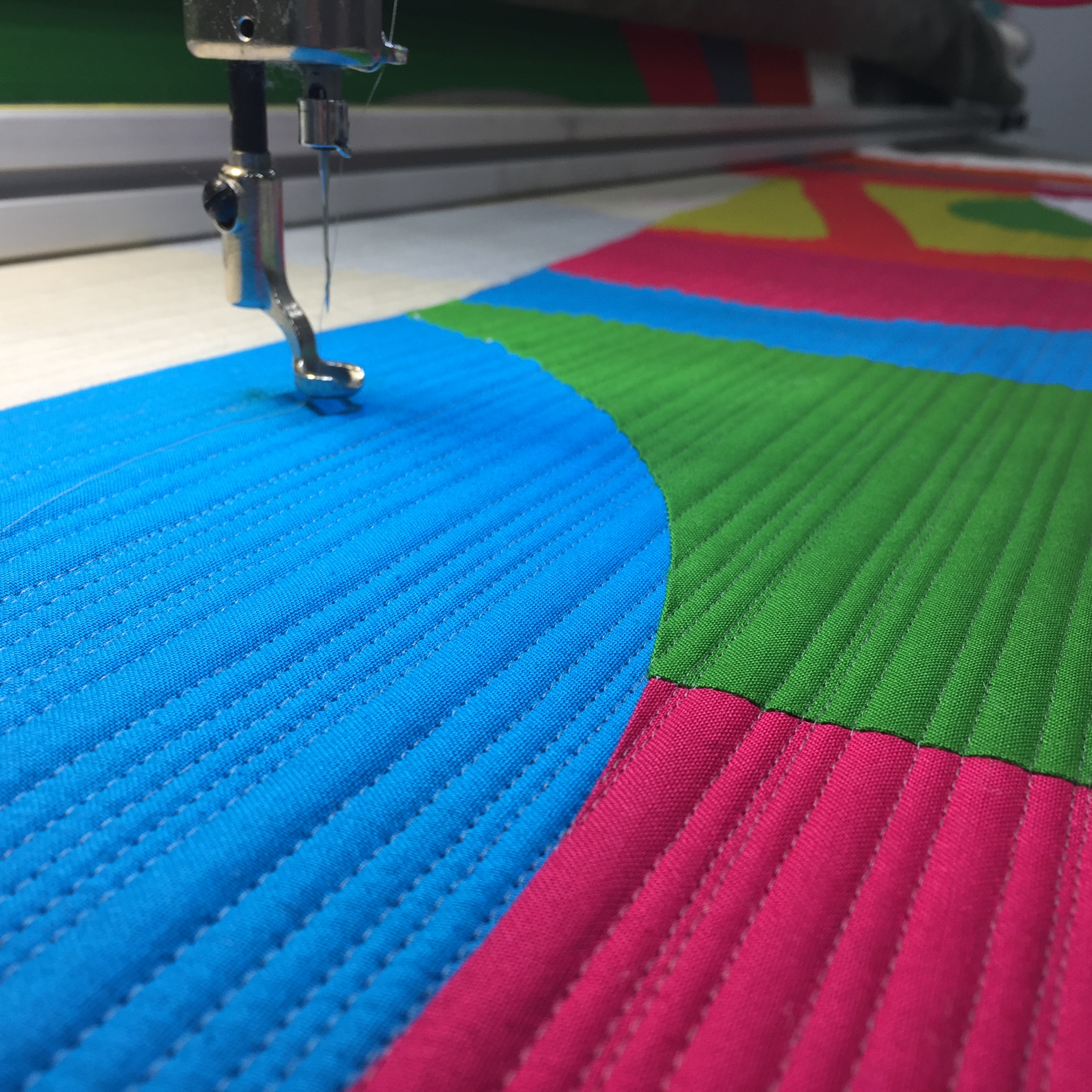 A machine is sewing on the fabric of a quilt.