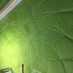A green quilt with a flower design on it.