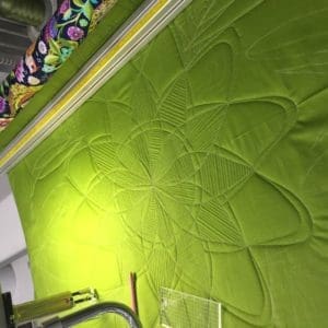 A machine cutting fabric with green fabric on it