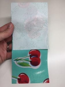 A person holding up a piece of paper with cherries on it.