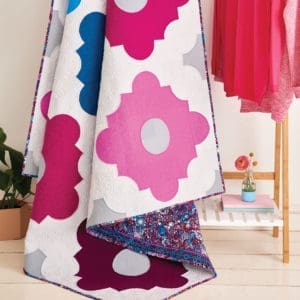 A pink and blue flower quilt on the floor