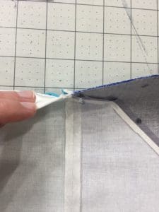 A person using scissors to cut fabric on the cutting mat.