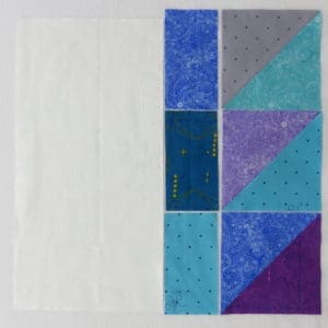 A white sheet with blue, purple and grey squares on it.