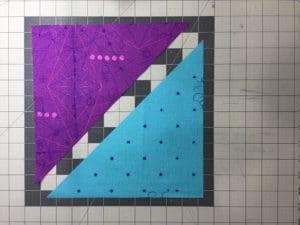 A purple and blue quilt on the floor of a subway station.