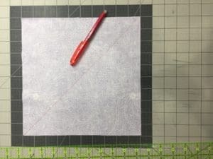 A red pen and paper on top of a cutting mat.