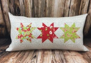 A pillow with three different colored stars on it.