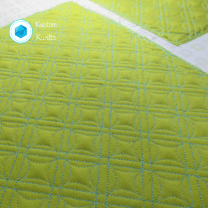 A close up of a yellow quilt with blue stitching