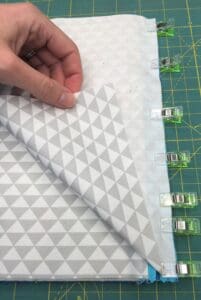 A person is sewing fabric on the cutting mat.