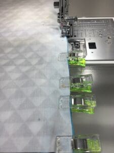 A machine is cutting fabric with green and white sewing machines.