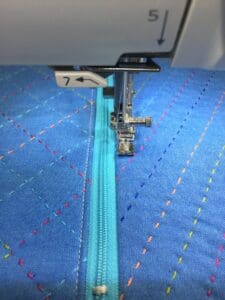 A machine is sewing on the blue fabric.