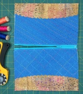 A pair of zippers and sewing supplies on top of a green cutting mat.