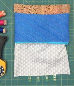 A sewing kit and some fabric on a green cutting mat.