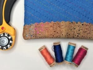 A pair of yellow headphones next to some thread and a blue bag.