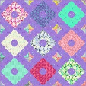 A purple quilt with different colored flowers on it.