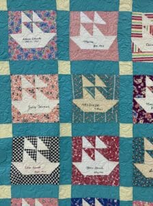A quilt with boats on it and names of the nine people who died in the sinking.