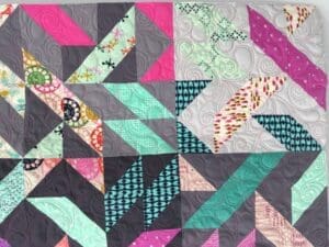 A quilt with different colored squares and triangles.