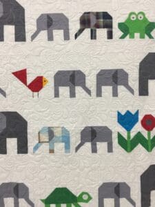 A close up of an elephant quilt with the elephants and birds