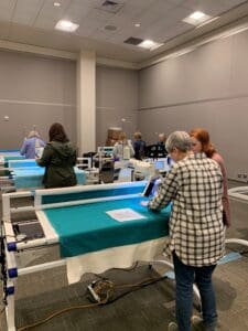 A group of people standing around tables with papers on them.