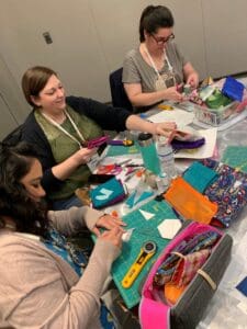 A group of women sitting around a table making crafts.