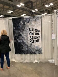 A woman standing in front of a large quilt.