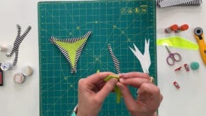 A person is sewing the fabric on a bikini top.