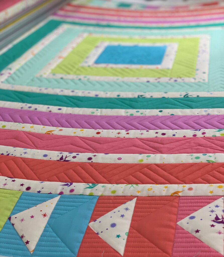 Detail of ruler work quilting on brightly colored cabin fever quilt