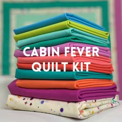 stack of colorful fabric for cabin fever quilt kit