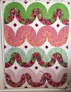 A quilt with pink and green designs on it.