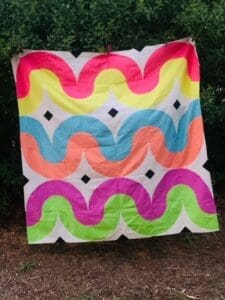 A colorful quilt hanging on the side of a tree.