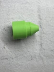 Small green plastic cone-shaped object on a textured surface.