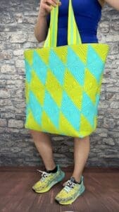 A person standing in front of a brick wall holding onto a bag