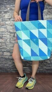 A person holding onto a blue quilt