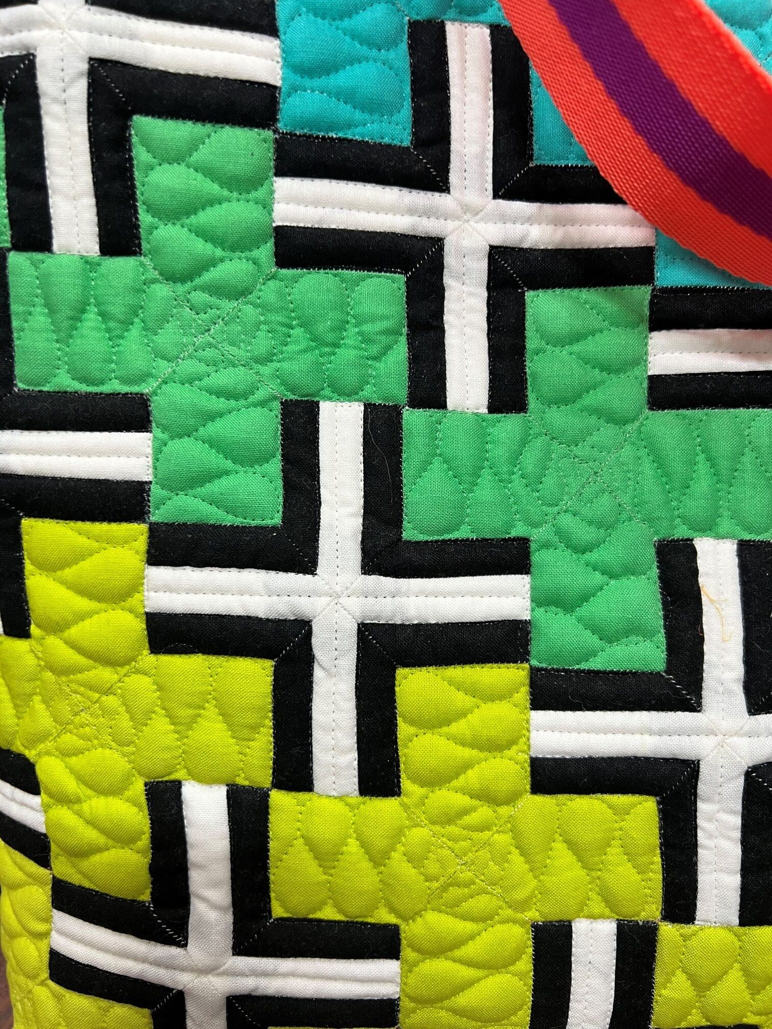 A close up of the quilt with black, white and green crosses.