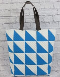 A blue and white bag sitting on top of a brick wall.