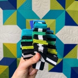 A person holding up a stack of fabric squares.