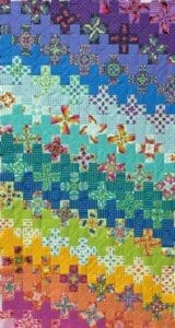 A quilt with crosses on it is colorful.