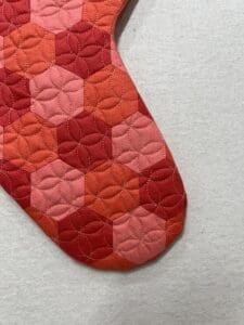 A red and pink quilt is shown on the floor.