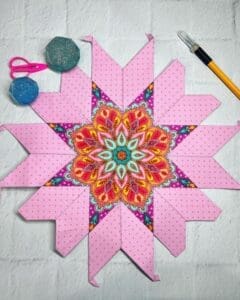 A pink quilt with a colorful star on it